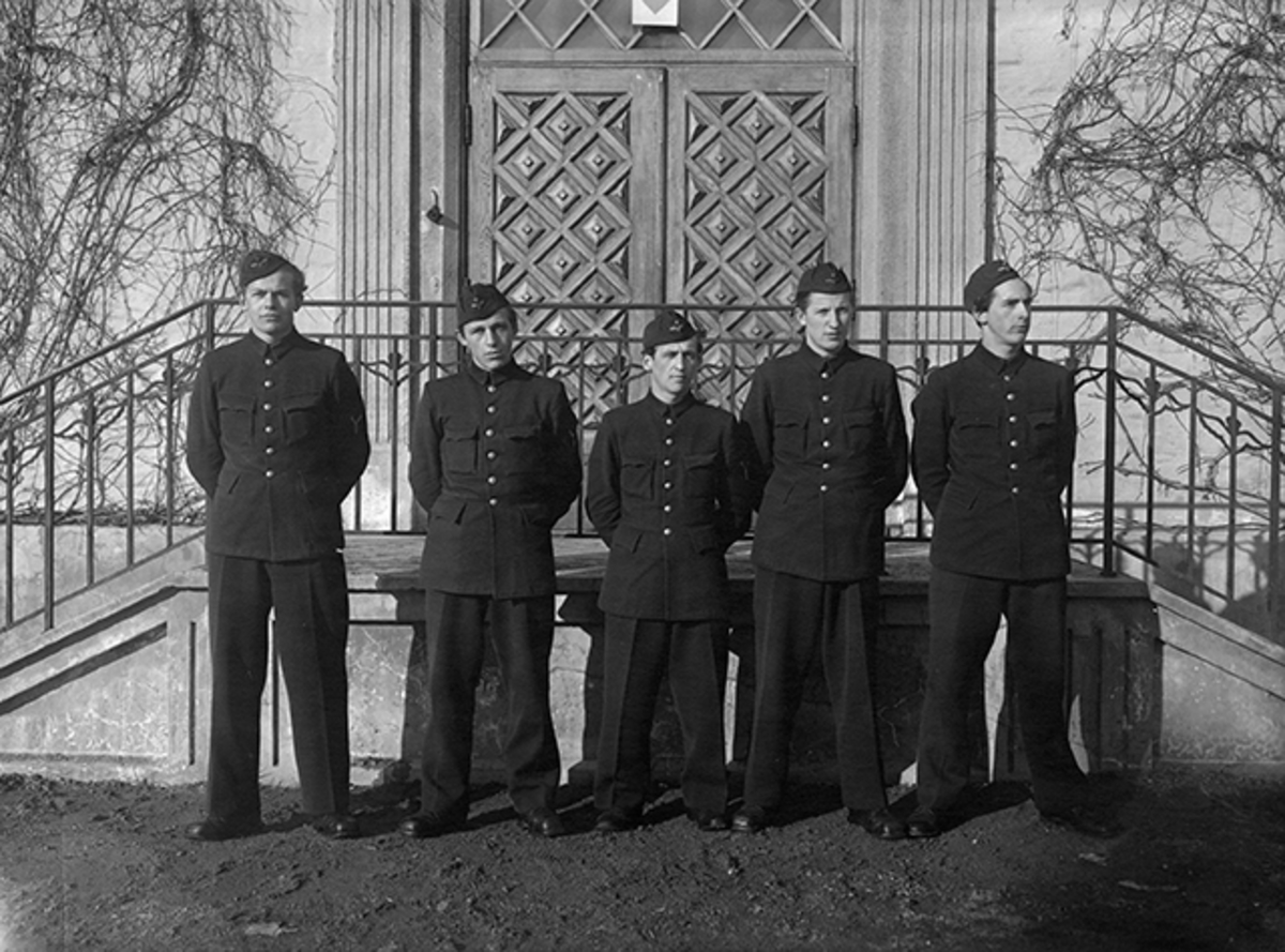 Grupporträtt av fem elever vid korpralskolan på F 2, 1944. Torpedmekaniker vid trappa.