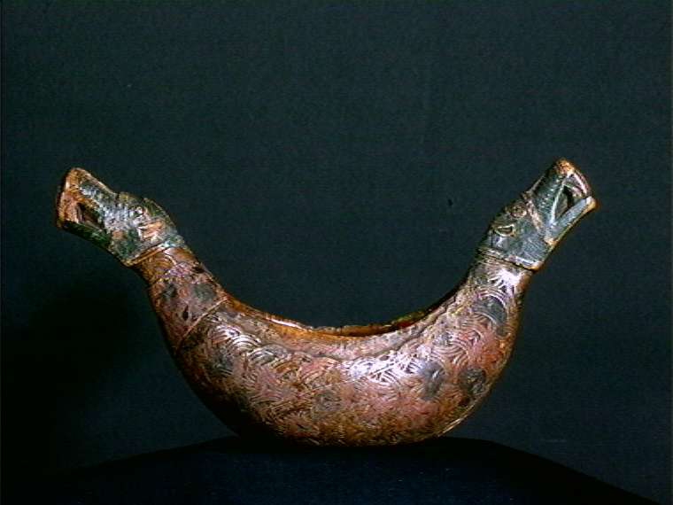 Bolle med håndtak formet som dragehovden. Flatskurd dekor: Geoometrisk bånd. Polykrom maling i flere lag.