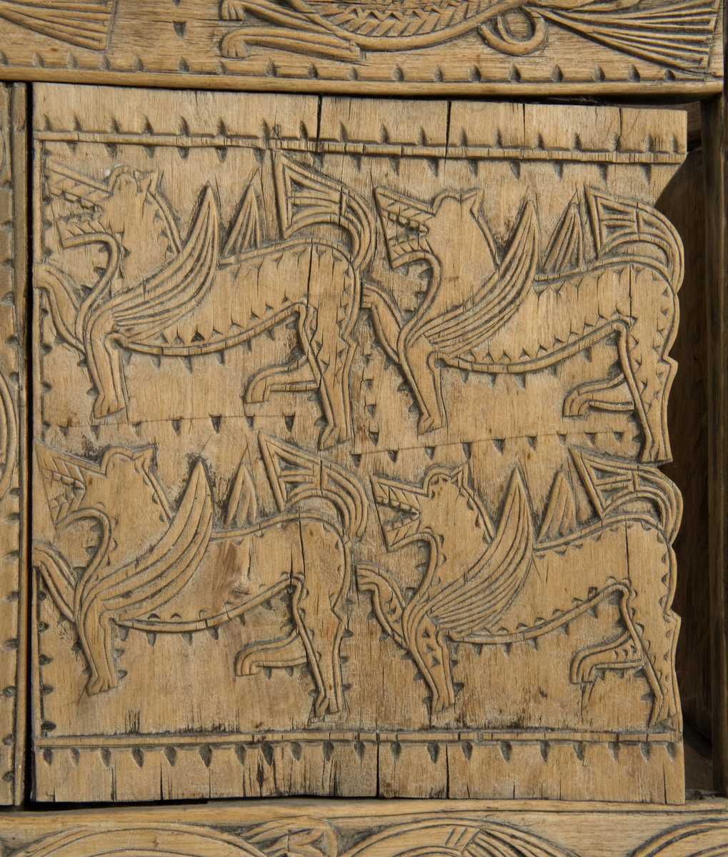 Fire søyler med skåret dyrehode-ornamentikk, sammenføyet med tverrbord og fyllinger. Bunn er åpen foruten to tverrstaver. Hele utsiden er rikt dekorert med utskåret dyr og ranker.