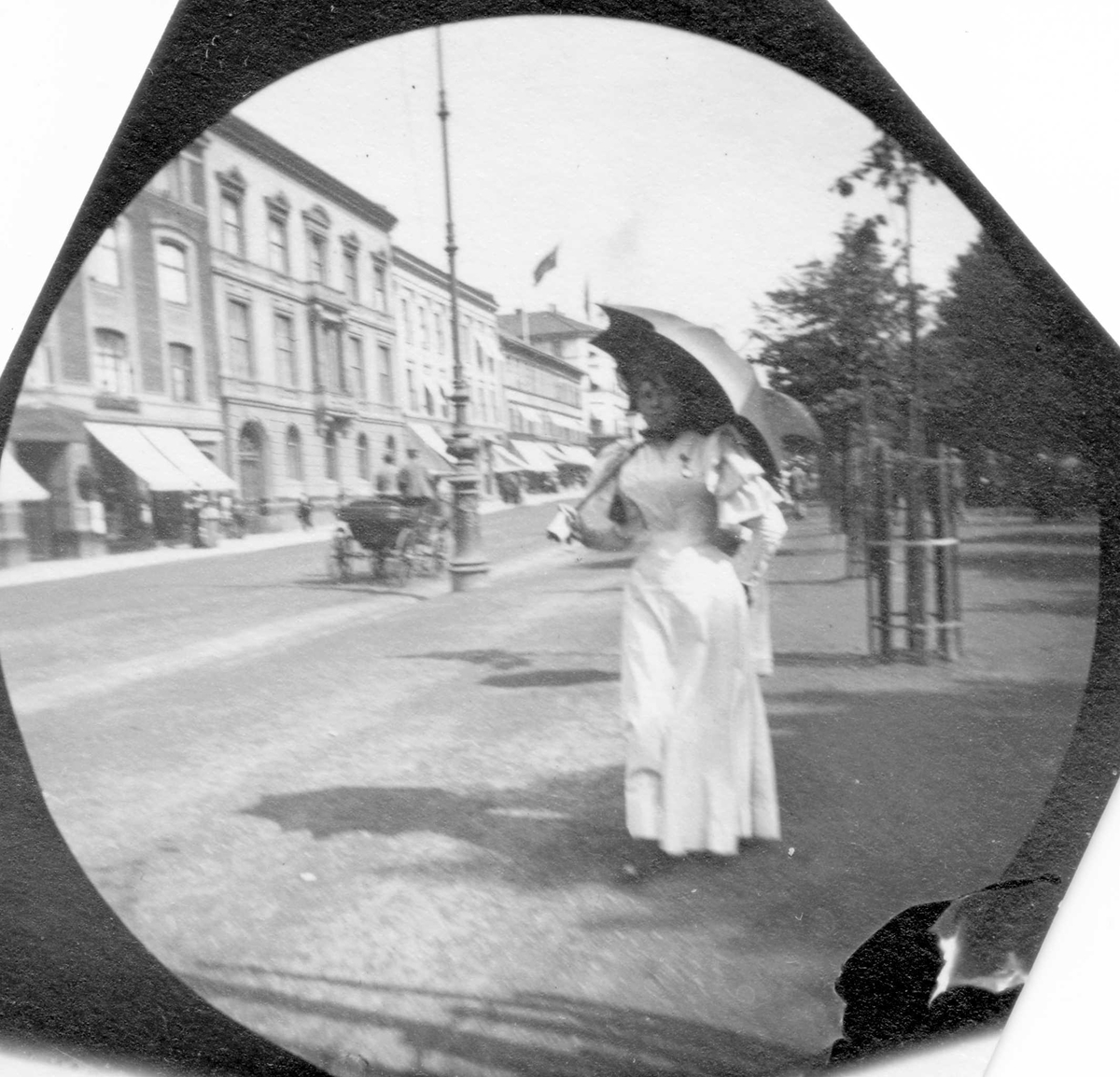 Fru Preuton spasere langs  Karl Johans gate, Oslo. Hestevogn i gata.