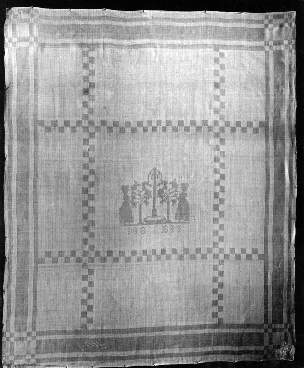 Hvit serviett med dame ved tre, stripebord. Vevet av Inger Johanna Møinichen på 1830-tallet. Norsk hjemmevevet damask.