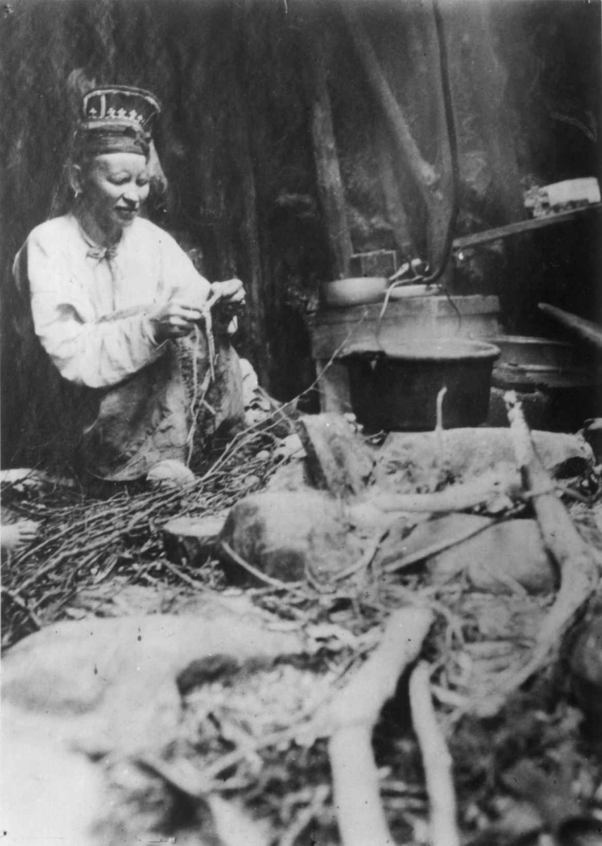 Skoltesame-kone, Tajana Feodotova Titoff, strikker ved kokestedet, antatt Sør-Varanger, Finnmark ca. 1900.