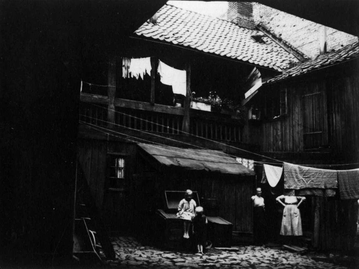 Oslo 1921. Bolig med gårdsrom. Svalgang med blomsterkasser, klesvask, to barn og to kvinner.