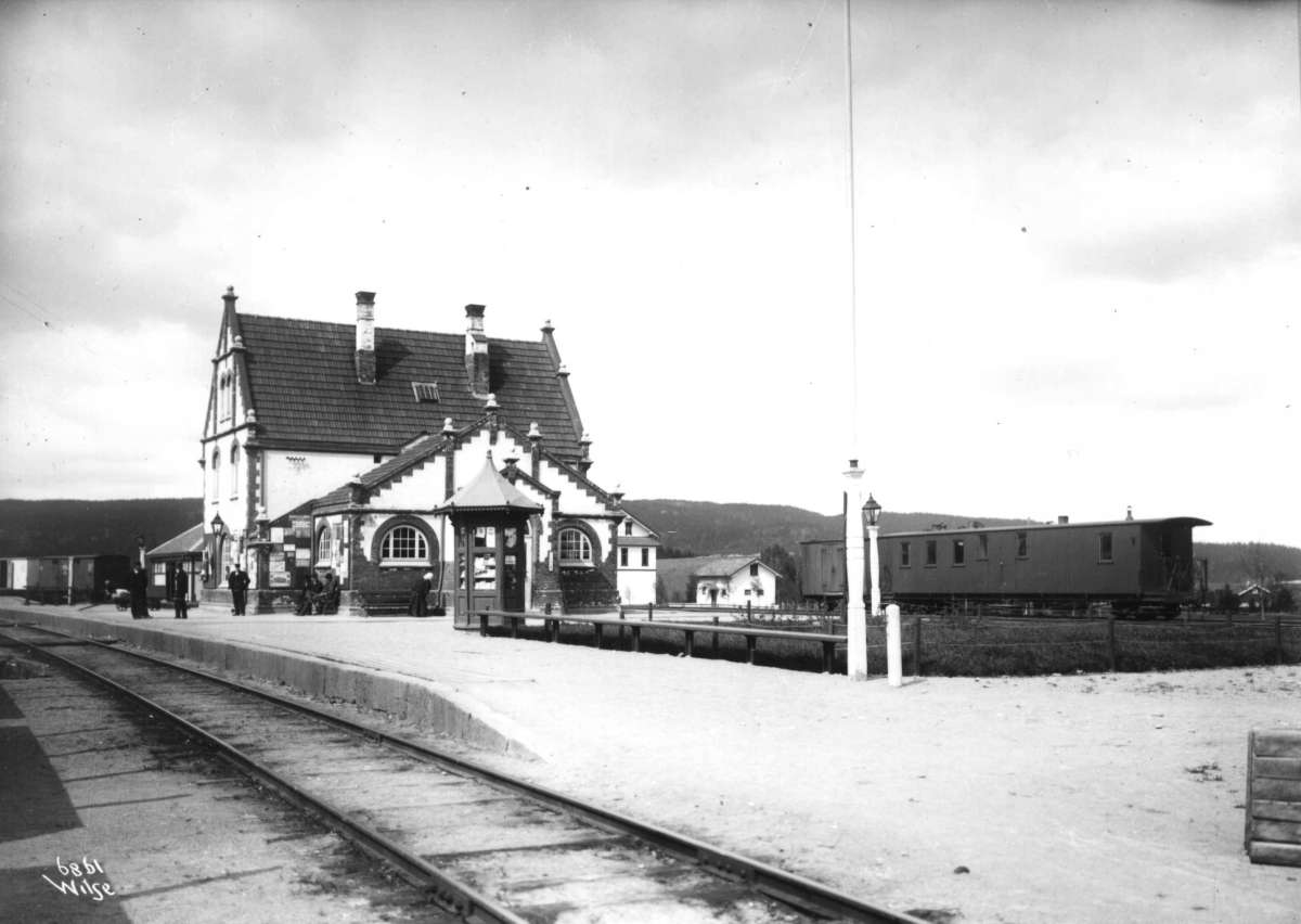 Sørumsand stasjon, Sørum, Akershus 1907. Stasjonen, reisende på plattformen, kiosk og jernbanevogn.