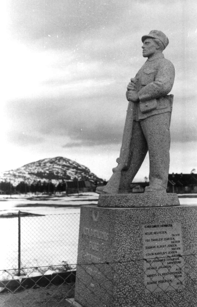 Monument over Alta bataljons falne  ved Altagård, en stående soldat med geværet foran seg. Den står på Altagård i Alta, Finnmark. Laget av Per Hurum (1949, granitt). I bakgrunnen ser man Komsafjellet.
