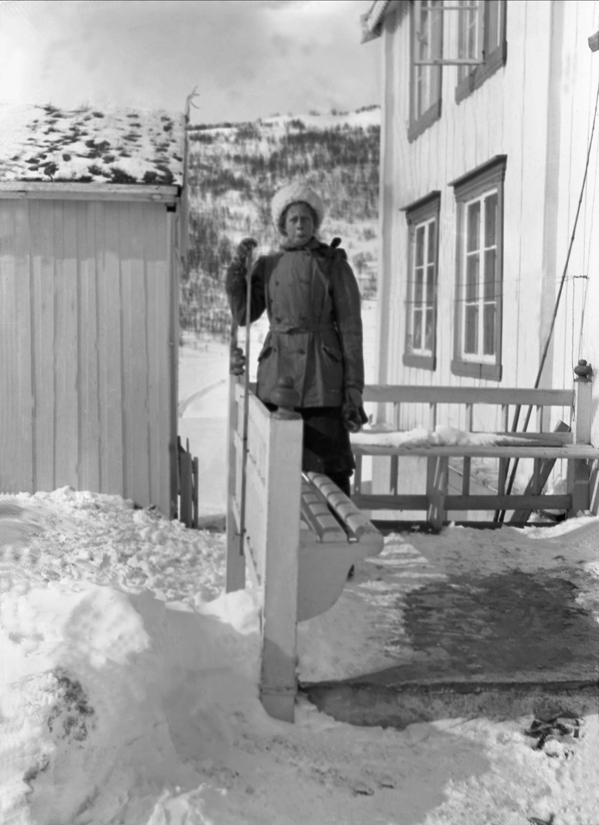 En kvinne står på en trapp utenfor et hus. Robsahm og Lund.