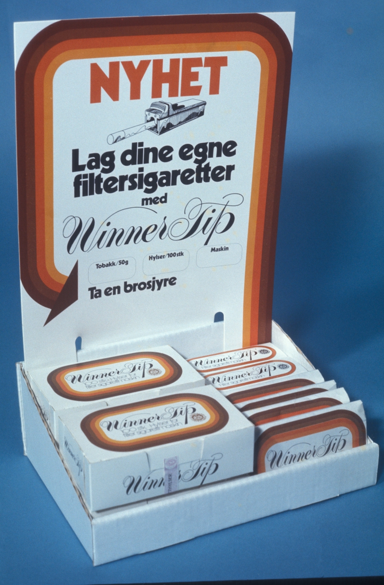 Reklamefoto av Winner-tip tobakk, sigarettmaskin og sigaretthylster i utstillingsmateriell til butikk. Fra presentasjon i forbindelse med introduksjon av Winner-tip i Norge i 1972.