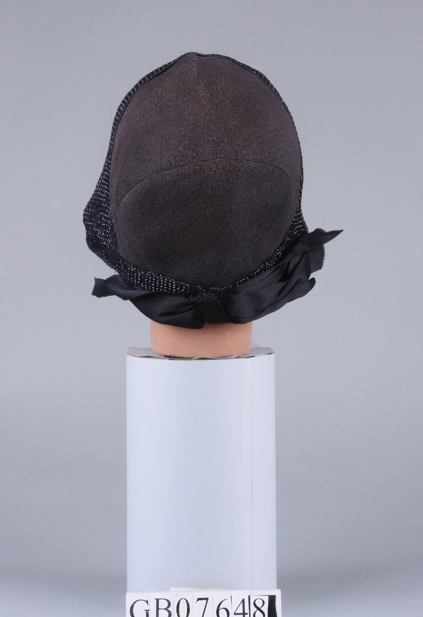 Bløt hatt med silkesløyfe bak. Pyntet med et 10 cm bredt vevet bånd av stråmateriale rundt hele kanten.