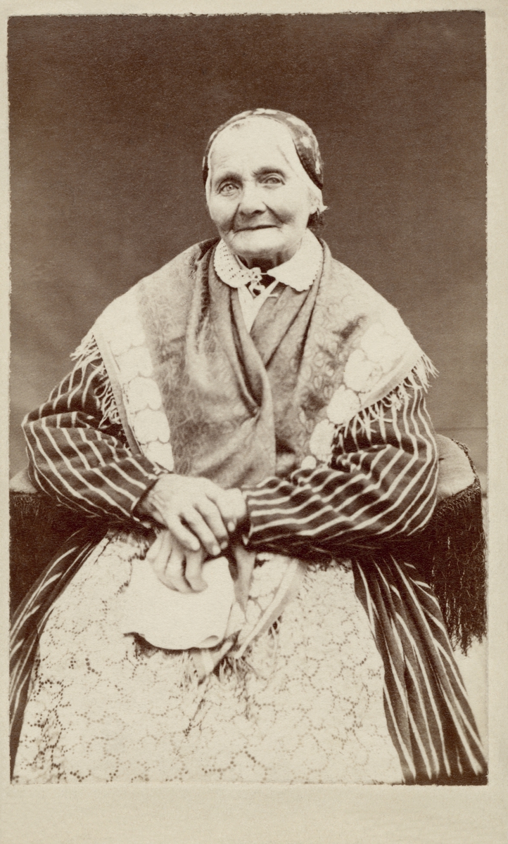 En äldre kvinna poserar i en sockendräkt