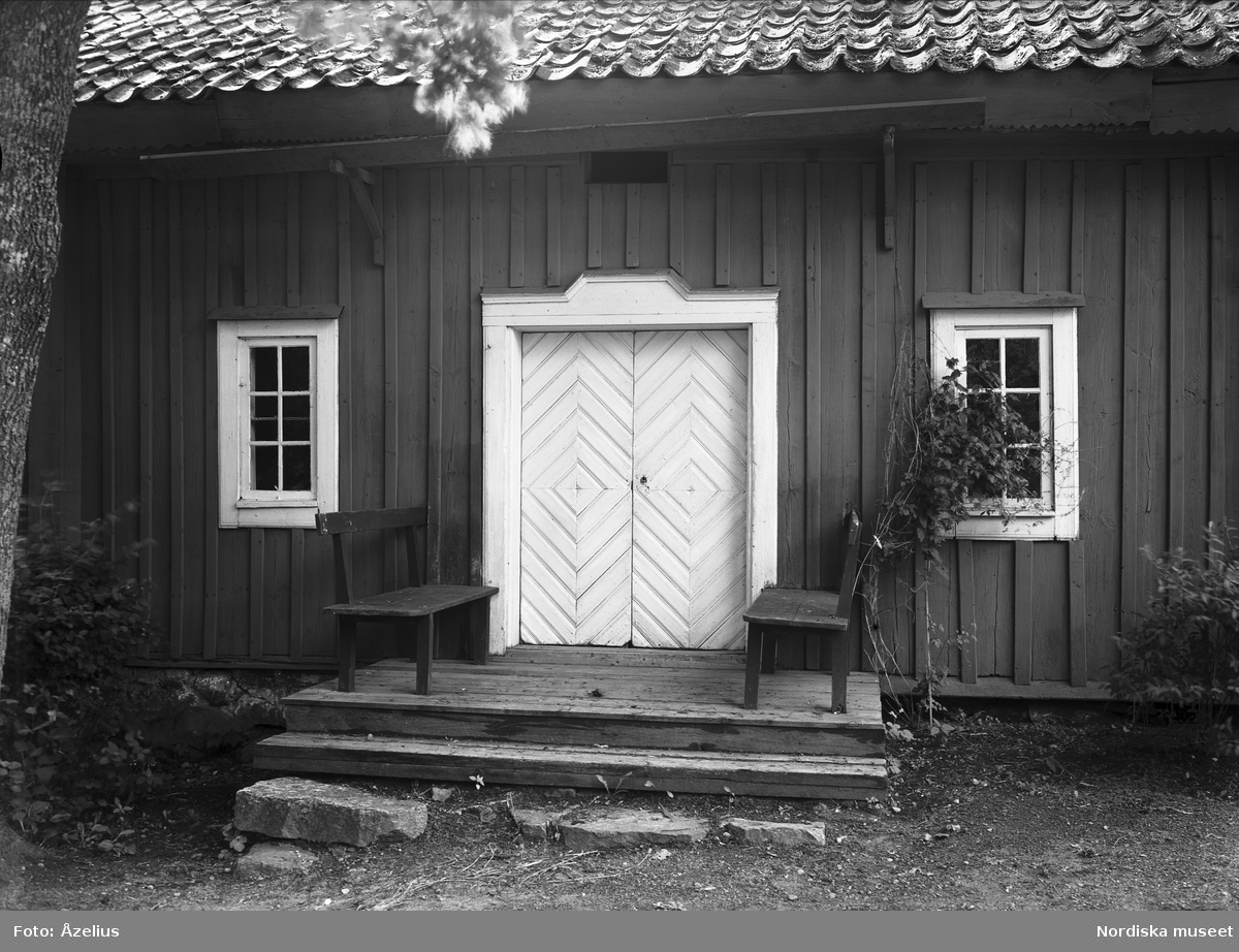 Prästgården i Helgesta socken, Villåttinge härad, Södermanland. Entrén med dubbeldörrar och trätrappa där två träsoffor står.