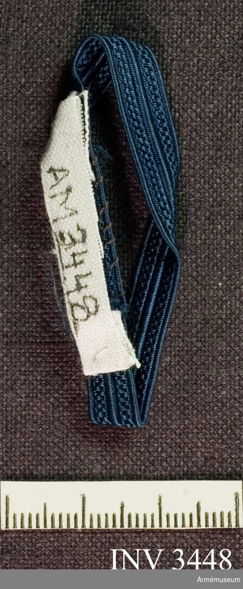Längd: 100 mm. Blått band, 7 mm, för vice tjänstegrenschef eller  detaljgruppchef SLK. Att fästas runt axelklaffens bas. Ett blått mönstervävt sidenband. Bäres ett på vardera axeln.