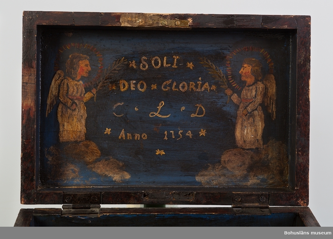 Rektangulärt med fasat lock. Locket har en spegel inramad med pärlstav. På spegeln är en målning av Golgata med två herdar i förgrunden.
I övrigt har den en röd och svart grundmarmorering.
Framstycket har målad blomdekor samt texten "Anno 1754 C.L.D"
Sidostycket har gul schablon i alla hörn.
Inuti är en målning på blå botten föreställande två änglar samt texten "SOLI DEO GLORIA [endast Gud tillhör äran] C.L.D Anno 1754".
Nederdelen är målad med blå färg inuti.
Locket har spår av tidigare gångjärn på främre kanten samt efter åsbleck på bakre kanten där gångjärnen nu är fastskruvade.
Sekundärt lås på framstycket.
Fyra tassar undertill, varav en är sekundär.
Kan vara en friargåva.

Under reformationen myntades fem punkter vilka är måttstock för en sund kristen tro.
SOLA GRATIA - endast nåd
SOLA FIDE - endast tro
SOLA CRISTOS - endast Kristus
SOLA SCRIPTURA - endast Skriften
SOLI DEO GLORIA - endast Gud tillhör äran

Litteratur: Knutsson, Johan, Friargåvor, Nordiska museets förlag, Stockholm, 1995.

Ur handskrivna katalogen 1957-1958: 
Syskrin, av trä, målat
Mått: 28,5 x 19 x 14,5 cm; lockets ovansida: Golgata, herdar i förgrunden; en pärlstav runt målningen; insidan2 änglar, "Soli Deo gloria C L D Anno 1754; å skrinets framsida: "Anno 1754 C L D", jämte en målad blomslinga. Ngt skamfilat, låset defekt.