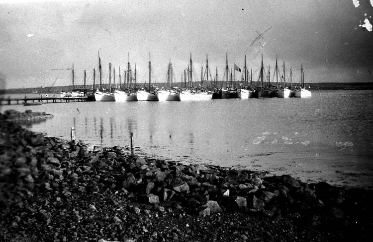 Enligt tidigare noteringar: "Bohuslänska fiskebåtar i hamn i Baltasound, Shetland, under pingsthelgen 1933. Tredje båten (svart kutter) från höger är LL 59 "Olive" av Grundsund. Repro av foto tillhörande Ernst Gullman".