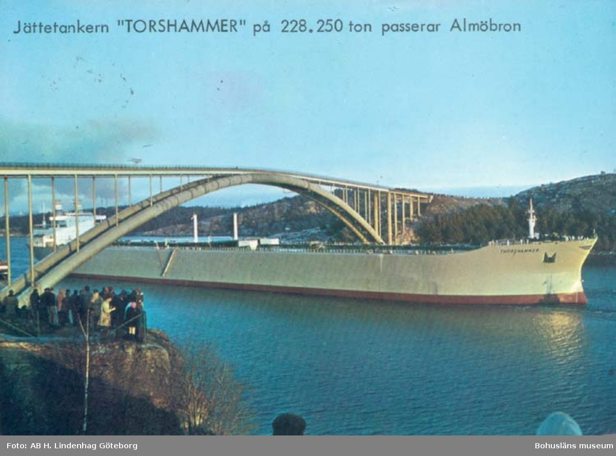 Tryckt text på kortet: "Jättetankern" Torshammer på 228.250 ton passerar Almöbron."
"Jättetankern" Torshammer" passerar Almöbron 6 dec. 1969. Tankern är byggd vid Uddevallavarvet och mäter 228.250 ton, längden är 325 mtr., bredden är 48 mtr., höjden från köl till radar 53,7 mtr. Fart vid full last 16,3 knop. Vid passerandet av bron som är 42.5 m. hög, hade Torshammer en frigång på 1,5m.