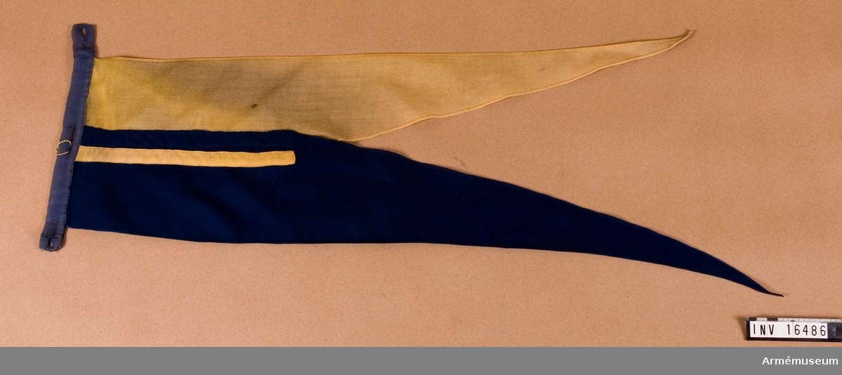 Tillverkad av blå och gul bomullsduk, så kallad flaggduk. Fästes på lans m/1851 med det blå partiet uppåt, överst.