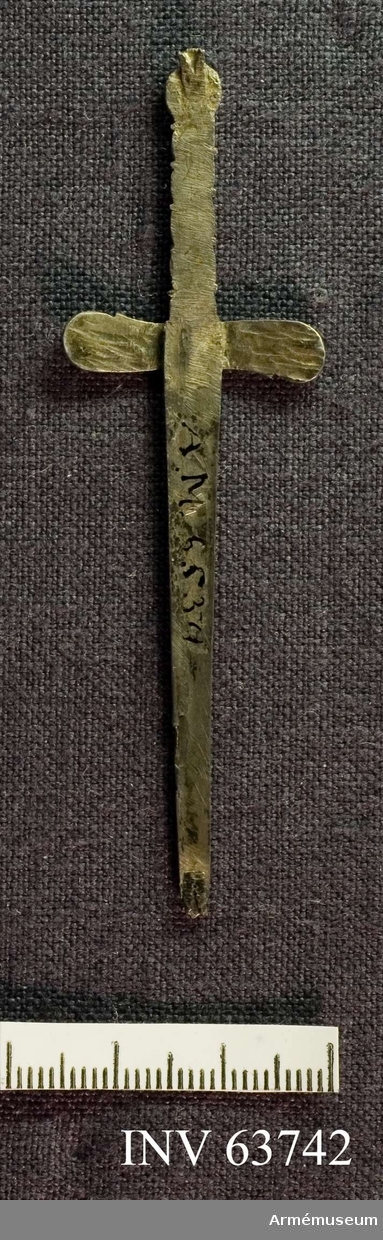 Grupp M II.
Ett svärd av silver med vridet ornetat fäste. I svärdets spets en liten ögla. Svärdet bars med fästet nedåt.
