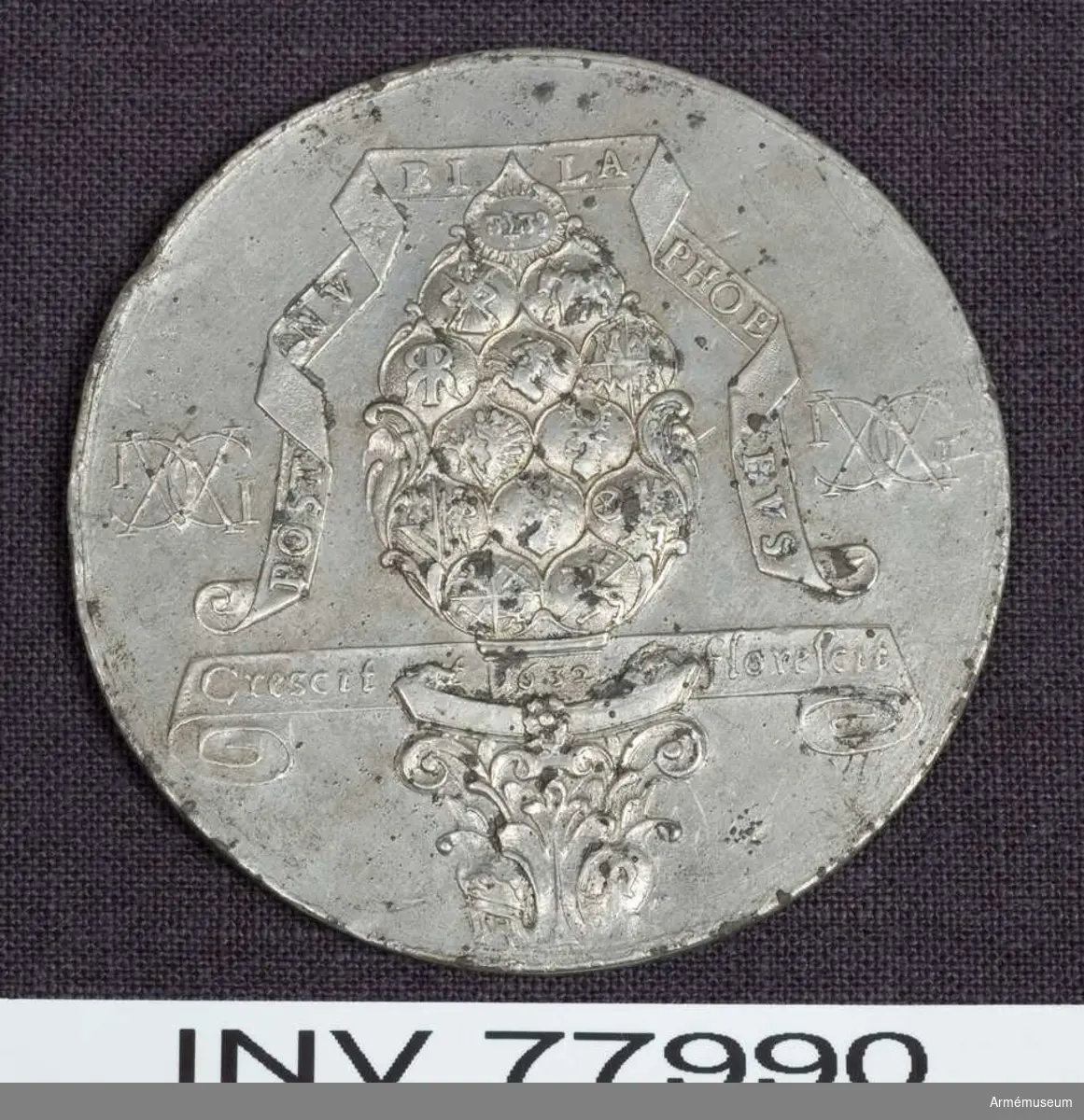Grupp: M.

Medalj. Gustav II Adolf. Augsburg öppnar sina portar för Gustaf II Adolf 1632 den 14 april.
Kantskavet på flera ställen skadat i randen.

Åtsidan: POST NV BI LA PHOE BVS. på ett veckat band omkring "der Augsburger Pyr" (kotten staden Augsburgs vapenbild), vars fjäll består av 13 små sköldar, av vilka 12 innehålla magistratpersonens vapen, den 13de och översta ett strålande JHVH (med hebreiska bokstäver). Kottens skaft, varpå läses: 1632, står på ett pelarkapitäl, prytt med två vapensköldar. På ett band bakom pelarens skaft: Crescit et florescit. På ömse sidor ett dubbelt monogram av bokstäverna GA, vilk avse dels konungens namn, dels stadens antagna benämning "Augusta Gustava" (i st. f den äldre "Augusta Vindelicorum".). 
Frånsidan: GVSTAVA. ET. AVG VSTA CAPUT RELIGIONIS ET REGIONIS på ett veckat band, på vilket vilar Sveriges krönta riksvapen, omgivet av dubbelmonogramen, Sådana som på åtsidan men under kungliga kronan. Där under en planritning av staden med dess gamla och tillämnade nya befästning samt den närbeflytande Neckarfloden med en biflod och en bro. Inom grundritningen äro fyra ovala vapensköldar. 1: Frih. Bengt Oxenstiernas (guvernör i staden), 2: Greve Georg Fredriks av Kohenlohe (ståthållare), 3: Johan Baners (general av infanteriet), 4: Frans von Fraytossen´s (generalkvartersmästare; hade utfört ritningen).

Kopia. 
Beskrivning av: Prn.
