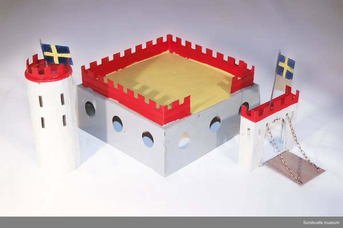 Leksaksfästning med ett löstagbart torn och port. Över dessa vajar två svenska flaggor.