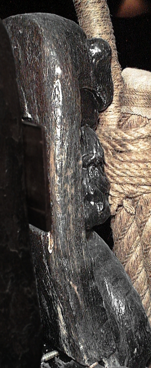 Skulptur föreställande en triton, svängd mot höger och återgiven i vänster profil.
Tritonen har böjd näsa och treflikig mustasch. På huvudet sitter en bladprydd hjälm med förtjockad framkant. Armarna är ersatta av långa, flikiga bladbildningar. Bålens övergång i den fjällförsedda fiskstjärten markeras av stora bladbildningar. Figuren avtecknar sig i hög relief mot det släta bakstycket. Tritonens stjärt döljs av stjärten från en under liggande drake, se fyndnummer 01769. På baksidan finns urtag för relingslisten.
Skulpturen är mycket välbevarad.

Text in English: Sculpture of a Triton, curved to the right in left profile.
The face with a curved nose and moustache in three parts beneath a leaf-decorated helmet with a thickened front. The arms are replaced by long, lobed leaf formations. The transistion between the male torso and the scaled fish-tail is decorated with large leaves. The sculpture is carved in high relief set against a plain back board. The rear is hidden by a powerful tail and wing of a dragon that lies below, see No. 01769. On the back board are notches to fit the railing.
The sculpture is very well preserved.