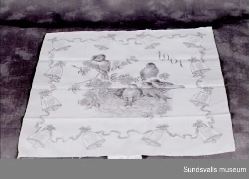 Näsduk av bomull med tryckt almanacksmotiv från 1901 föreställande ett fågelbo omgivet av tolv klockor med årets månader och dagar i.