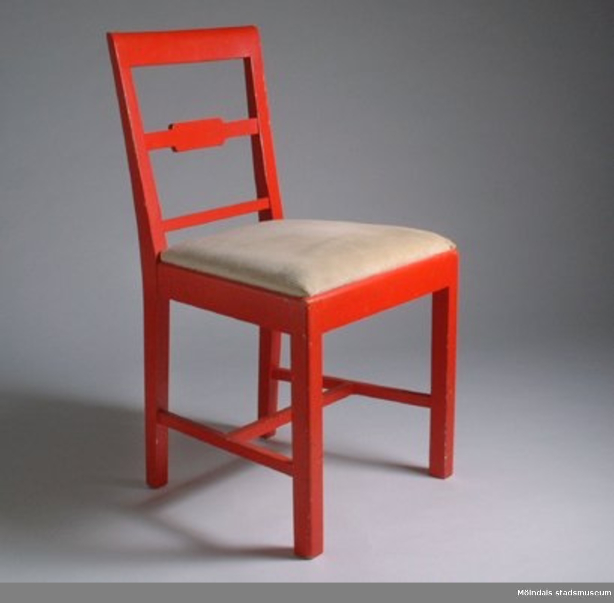 Röda stolar med beige manschesterfodrad sits. Ena stolens sits är lös.Under sitsarna står med blyerts ett namn och nummer.Tillhört personalbostad på 1940-tal.F.d. inv. nr MM 03025:1-2.