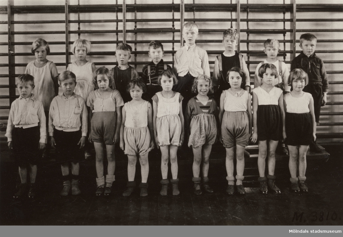Gruppfoto av flickor och pojkar i gymnastikskläder uppställda i gymnastiksal i Toltorpskolan.