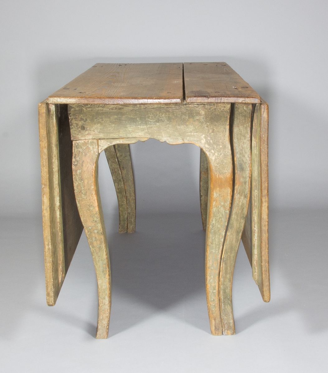 Slagbord i trä, sannolikt furu. Svängda ben, sarg med arbalètedekor. Rektangulär bordsskiva. Dubbla grindar som kan svängas ut och på vilka två större skivor kan vila.