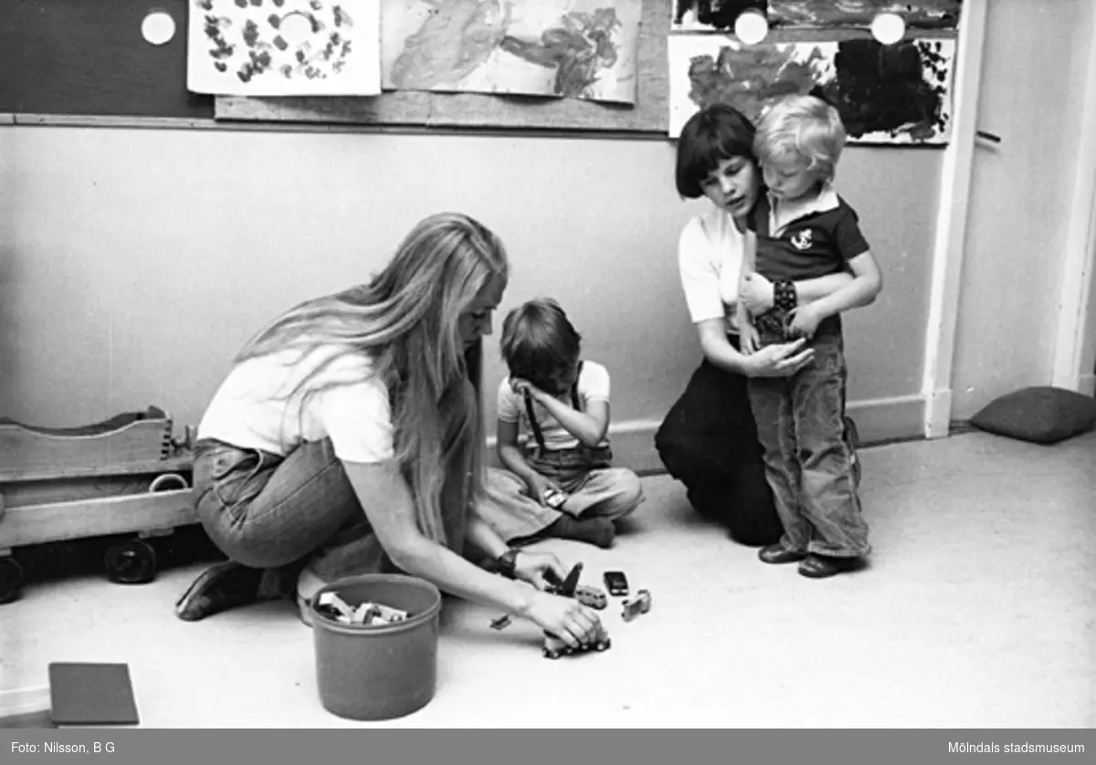Två barn och två fröknar leker med bilar på golvet. Holtermanska daghemmet maj 1975.