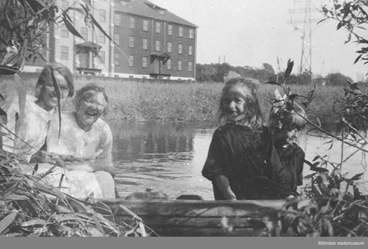 "En färd på Mölndalsån". Systrarna Elin och Gertrud Andersson med syskonbarnen Sonja och Aina Rundberg. De sitter i en båt vid Mölndalsåns strand 1927. I bakgrunden ses Svalöfsbolaget.