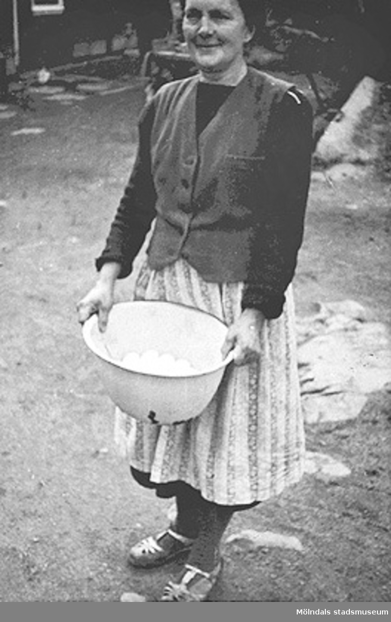"Mamma myser", 1920-tal i Kållered. En kvinna håller en skål full med ägg.