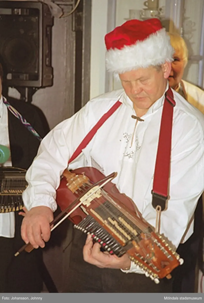Lommebôs spelmanslag spelar i Forscaféet på Mölndals museum 2002-12-22. Museitekniker Sven-Åke Svensson spelar nyckelharpa. På huvudet har han en tomteluva.