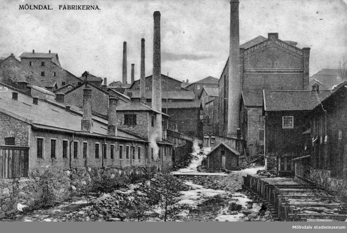 Vykort "Mölndal. Fabrikerna." som är utsikt från Forsebron upp mot Mölndalsfallen, cirka 1900-tal. Den långa byggnaden till vänster är Oljefabriken (O-fabriken) där man pressade Linolja. Den tillhörde SOAB. Nedanför ligger banvallen (eller den före detta banvallen) till industrijärnvägen, som gick mellan massafabriken Götafors och pappersbruket Korndal. Räls och slipers har tagits bort och snart tog man bort även den före detta banvallen. Till höger ses kvarnrännan som var vattenintaget till Papyrus. Den höga byggnaden längre upp är Stora Götafors.