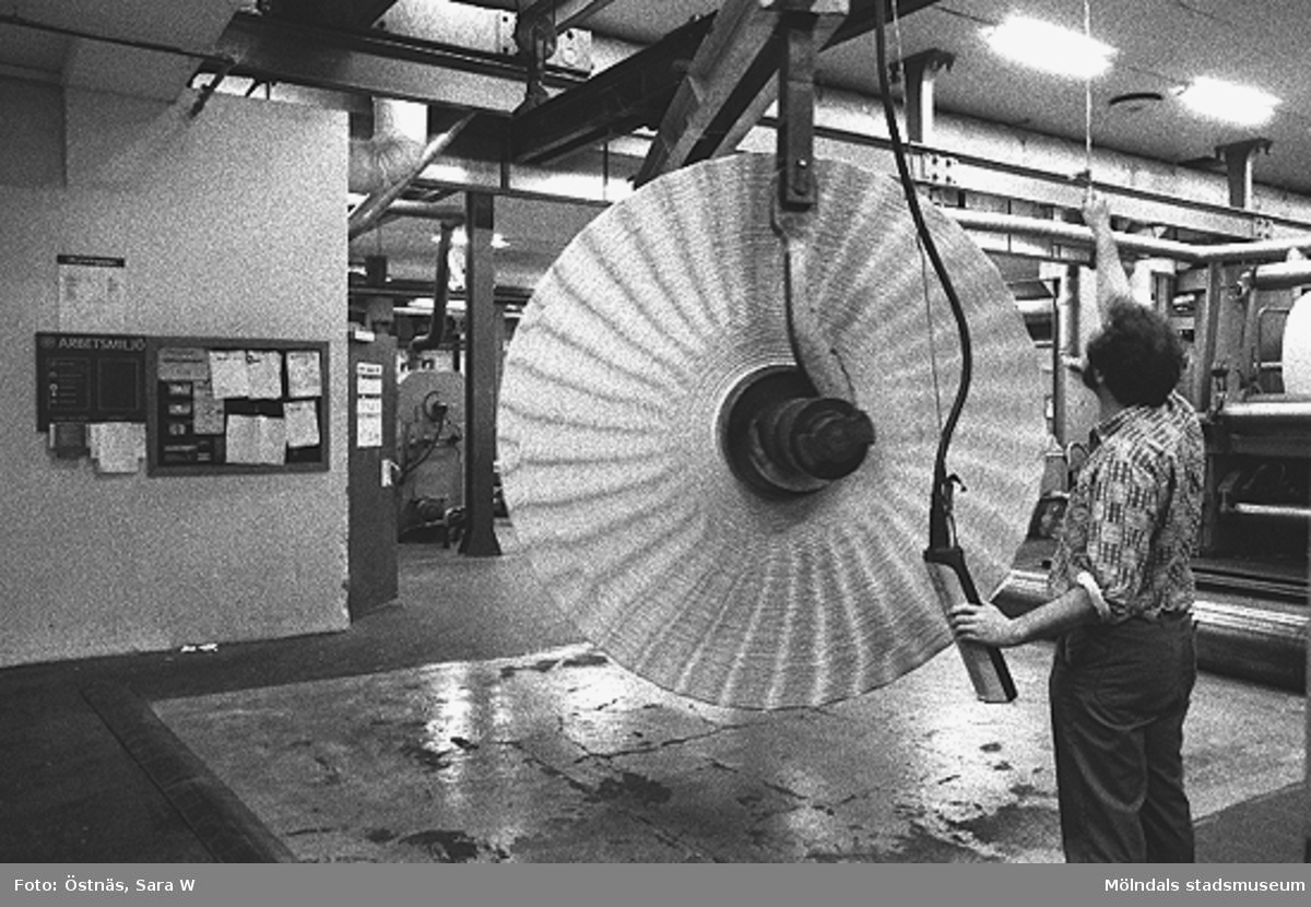 Aarno Aspbäck i arbete med en kartongrulle i Byggnad 6, 1980-tal. Bilden ingår i serie från produktion och interiör på pappersindustrin Papyrus.