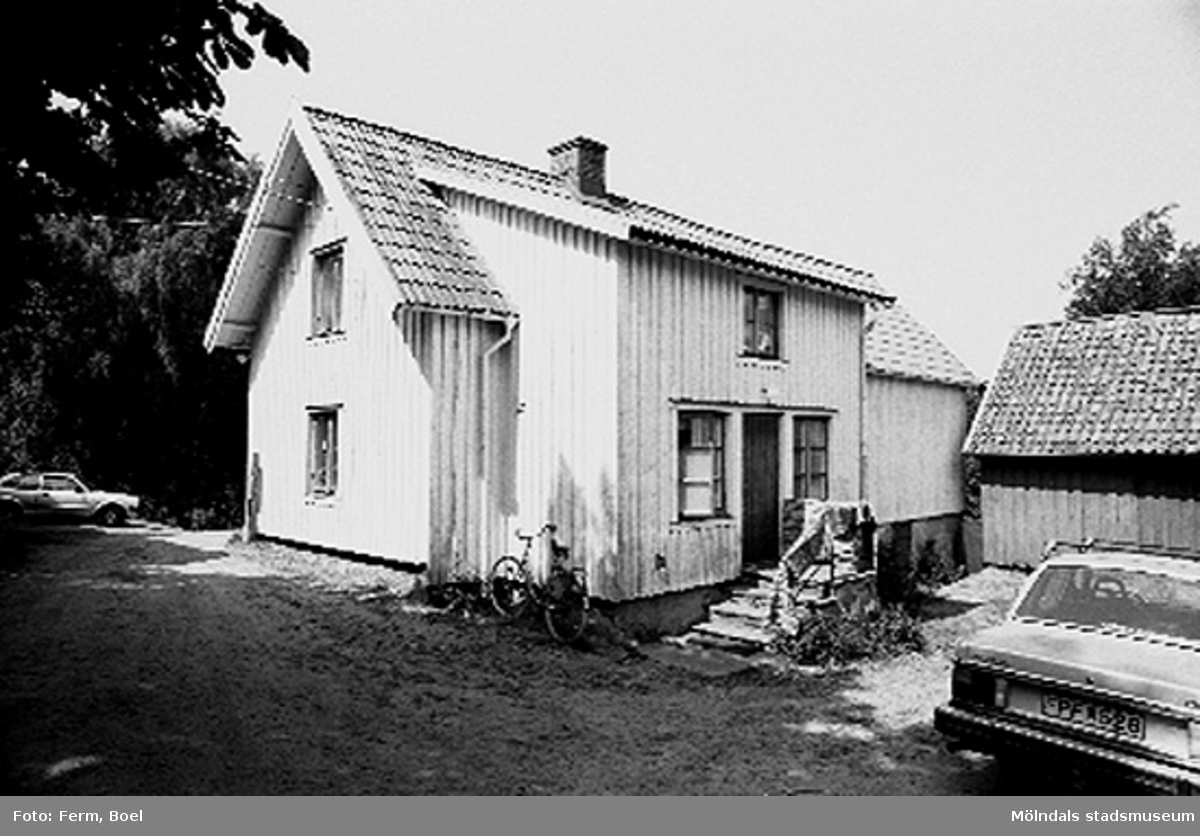 Bostadshus. Högen 2:1/2:2 i Kållered, 1992-06-30. Ett par bilar samt en cykel står utanför byggnaden.