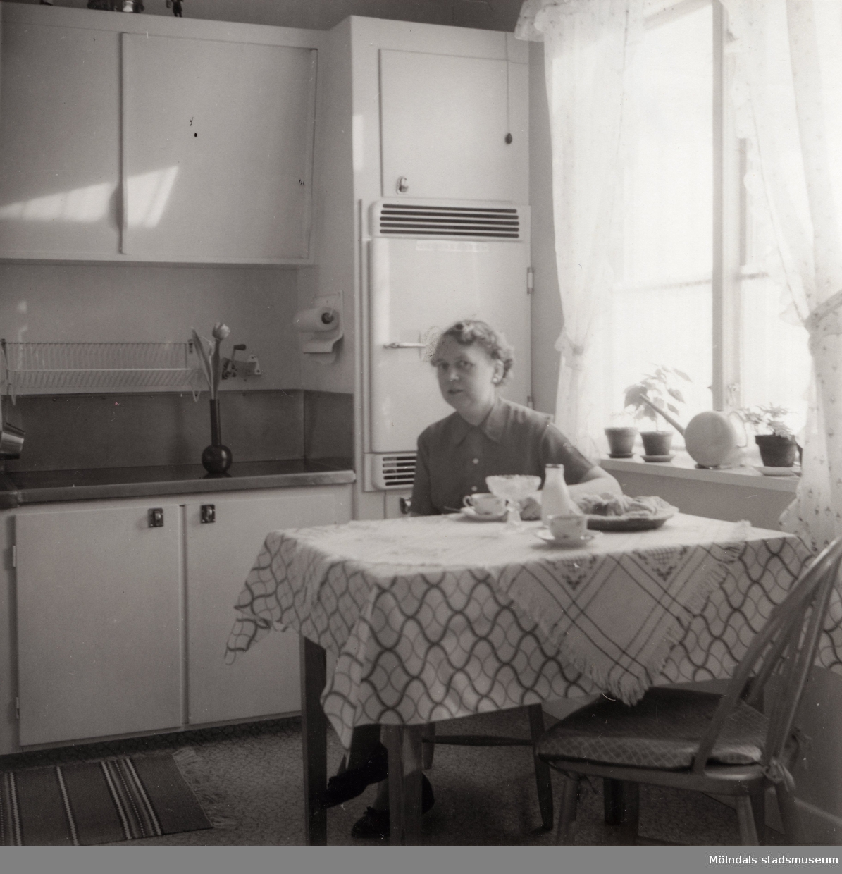 Inga-Lill Börjesson vid köksbordet på 1950-talet. Fotografi efter kylskåp installerats. Se även MMF2012:0048.