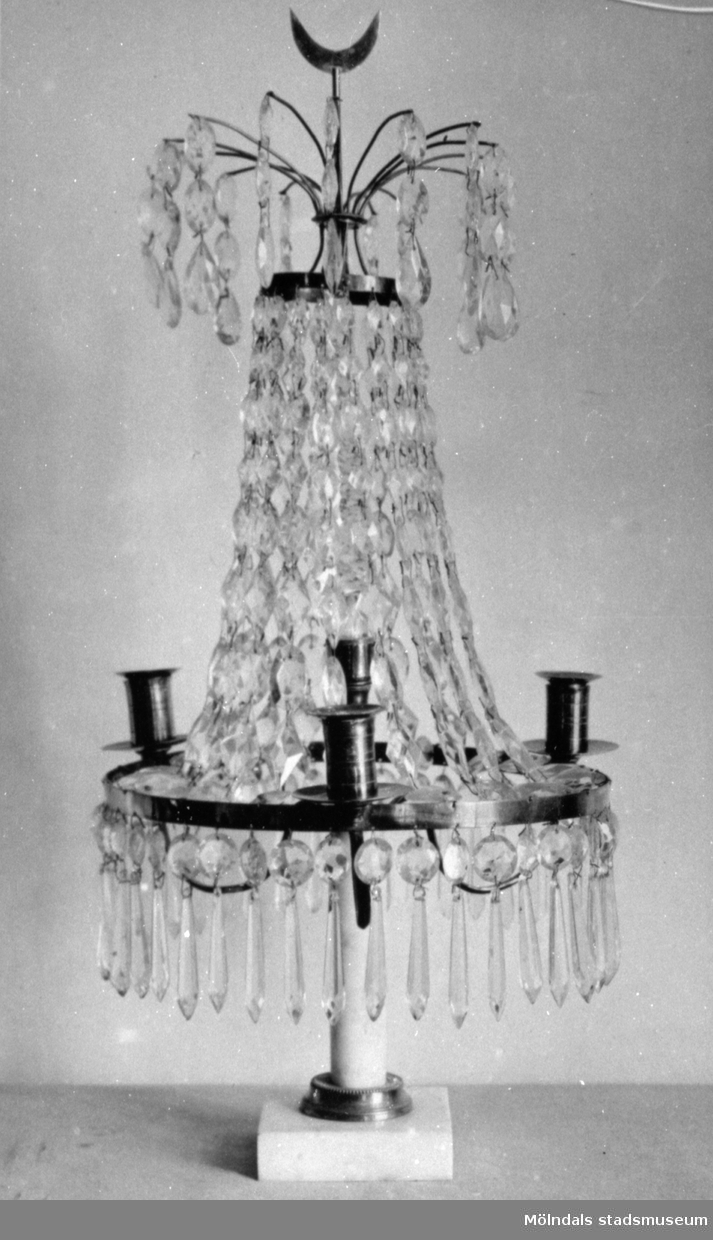 Gustaviansk lyster med slipade kristallprismor och marmorsockel med plats för fyra ljus. Gunnebo slott, 1930-tal.
