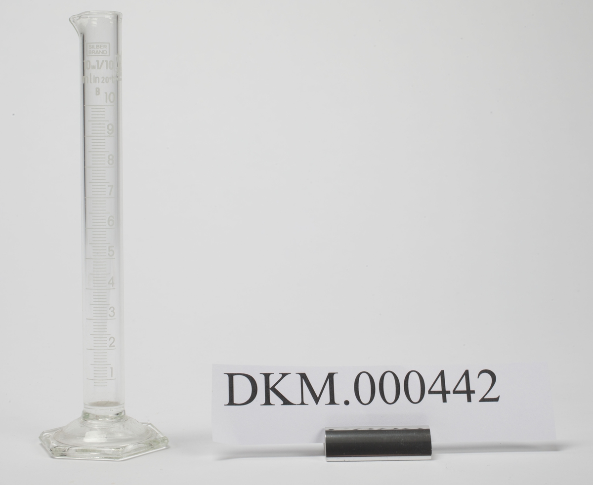Sylinder i glass som er åpen øverst, har måleskala på siden og sekskantet fot.