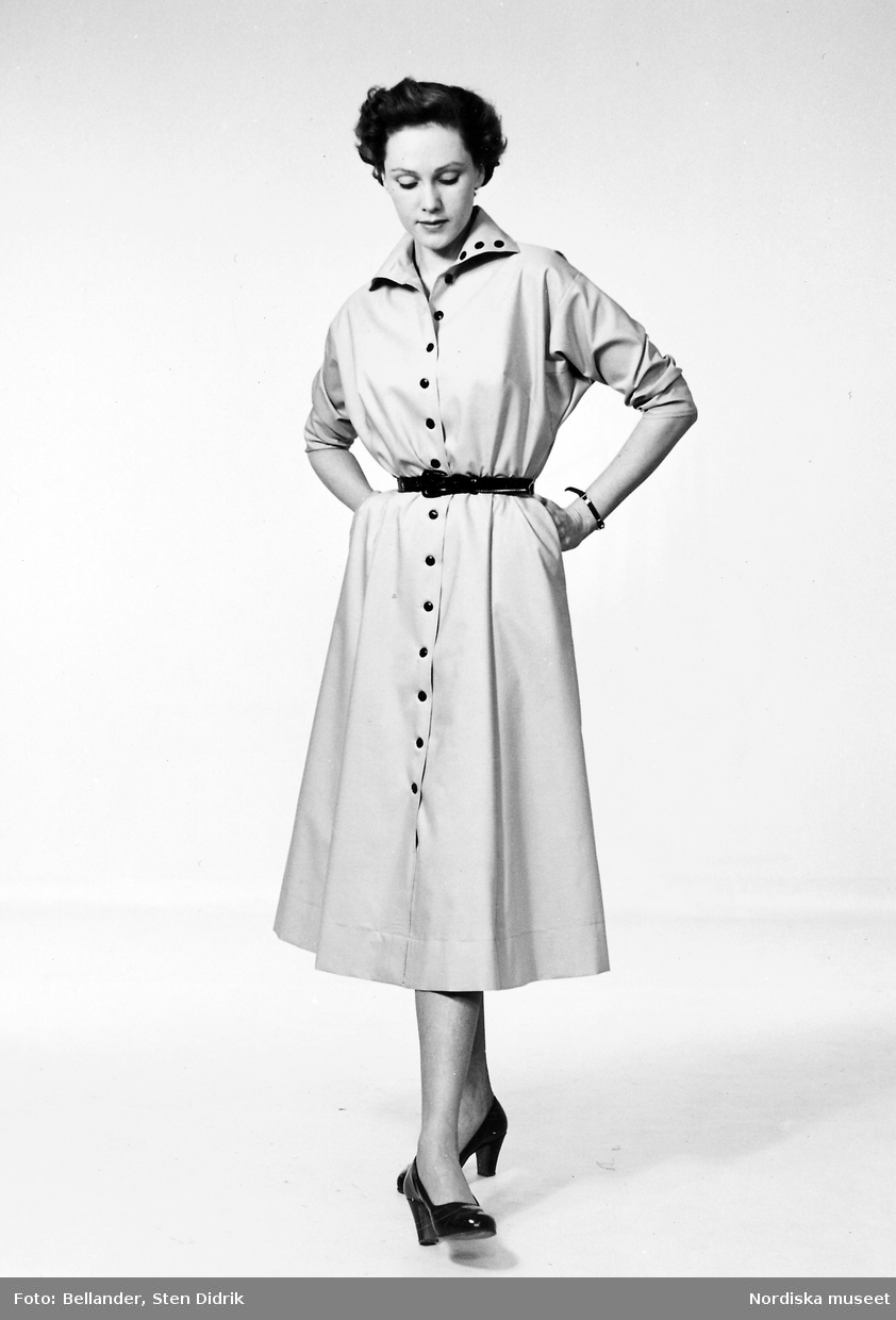 Modell, möjligen Margo Malmström,  i klänning, skärp och pumps i lack.