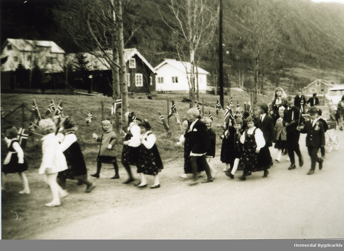 17. mai 1965. Barnetoget på veg til Hemsedal Bygdaheim i det toget svingar av frå riksvegen ved kommunehuset