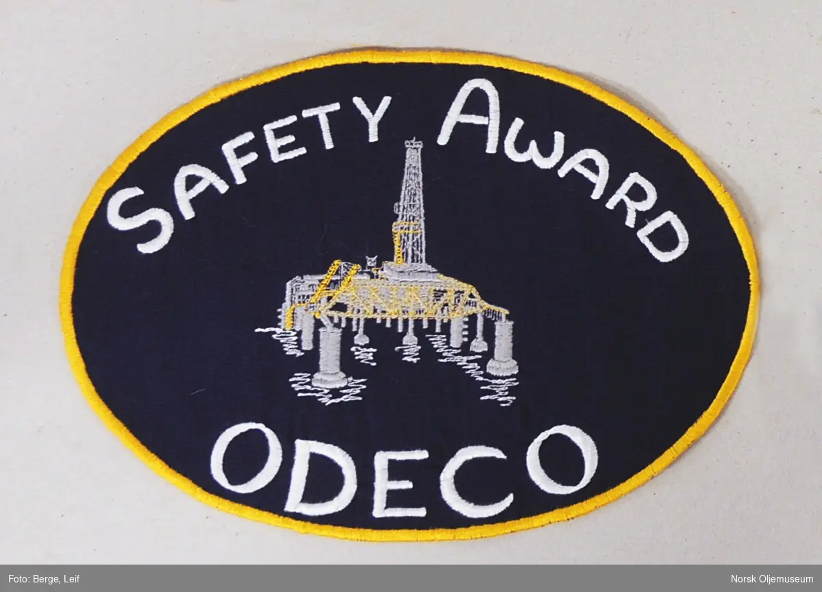 Tekstilmerke med brodert plattform og teksten "Safety Award" samt firmanavnet "Odeco".