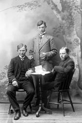 Studioportrett i helfigur av tre menn.