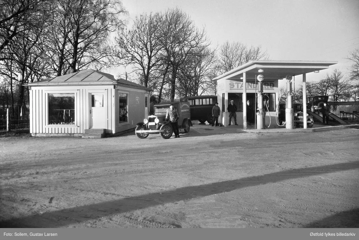 Bensinstasjon på Østsiden i Fredrikstad, Standard 1932. 
Datering ifølge fotograf G. Sollems protokoll (Fredrikstad Museum).
 
Bil nummer 2 fra høyre er en Ford A-modell 1928-29, reg.nr. B-10229, 
Bil nummer 1 fra venstre: Chevrolet varebil 1929-31. Tekst på varekassen: C.W.Johansen . Bakeriforretning. Reg.nr. B-1015X (Siste siffer uleselig).
Bil nummer 1 fra høyre: Reg.nr. B-10432