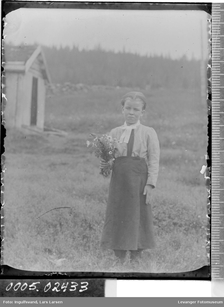 Portrett av jente som holder blomsterbukett i helfigur.
