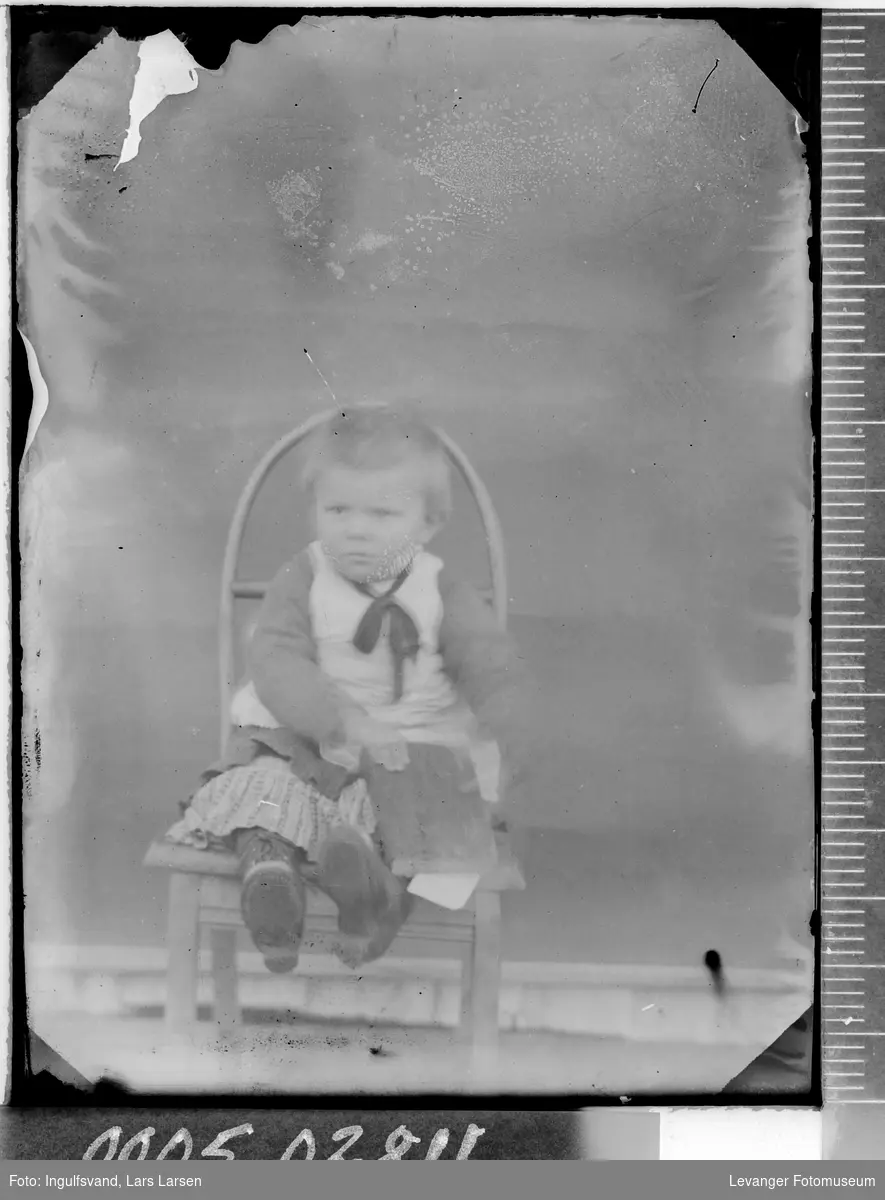 Portrett av et lite barn på en stol.