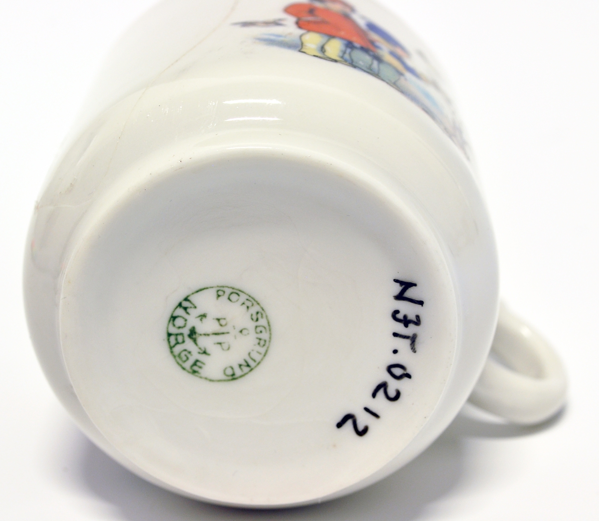 Liten kopp med hank til barneservise, hører sammen med skål av typen NJT.0211.
Modell:
Motiv: Overføringsbilde
Fabrikkmerke: Grønt anker med PP og PORSGRUND - NORGE, i sirkel (1913-1930).