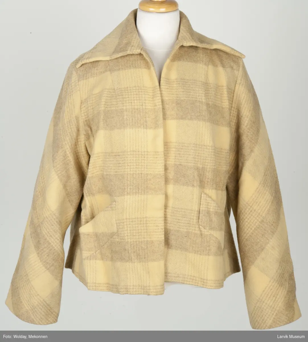 Kort jakke med krave, lommer og lange ermer. Ruter i gule og lyse brune farger.