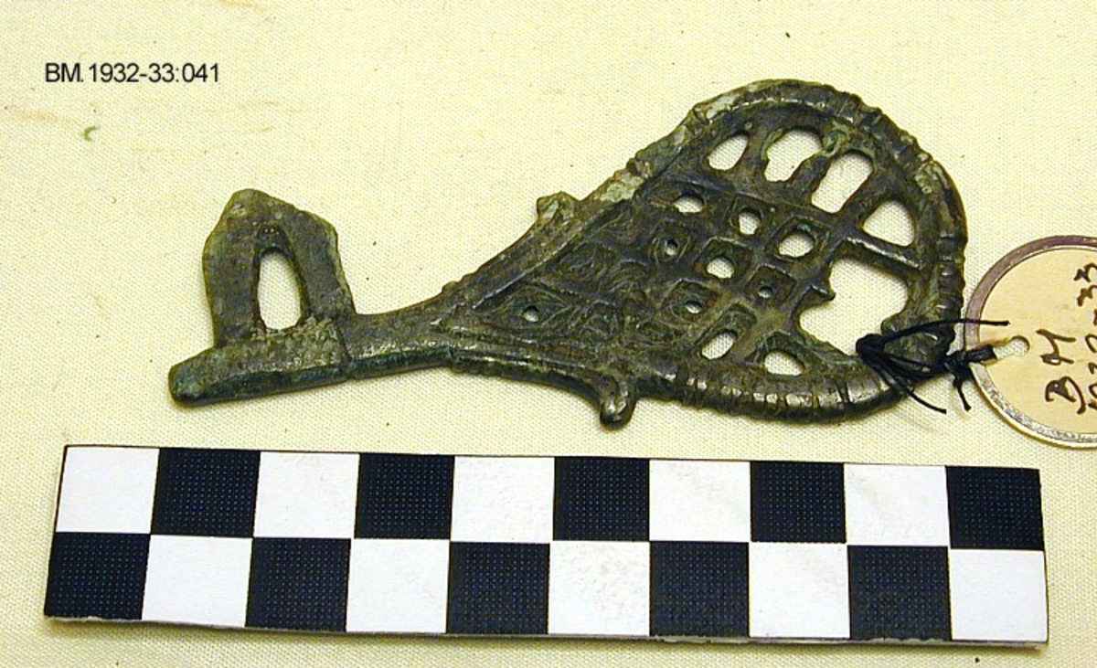 Fra protokollen (J. S. Munch): Bronsenøkkel av form som Jan Petersen: Vikingetidens smykker, fig. 262, med flatt, pæreformet skaft, innvendig ornert med et gitterverk. Skjæret er helt likt typeeksemplaret, med tre småtagger ytterst i hvert hjørne av trekanten mens selve håndtaket er bredere enn typeeksemplaret og  har tverriflet bøyle ytterst, og to små tagger, en på hver side litt oven for overgangen til skjæret. Funnet i jorda.