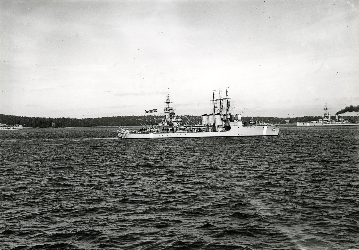 Tre vedettbåtar av Jägaren-typ förtöjda vid varandra. Nummer 44 är Väktaren.
Längst till höger pansarskeppet Drottning Victoria.