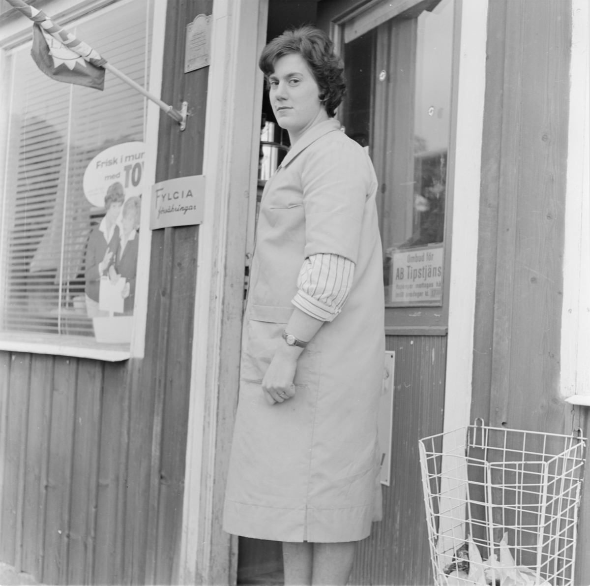 Kvinna utanför "Hagby diversehandel", Uppland 1962