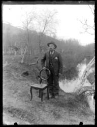 Mann stående ved en stol ute